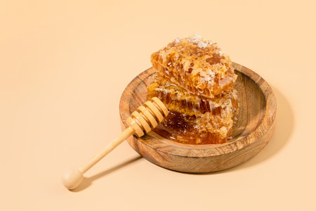 honey and honey dipper stick in a wooden bowlの写真素材