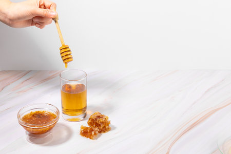 hand motion of putting honey in a glass of honey waterの写真素材