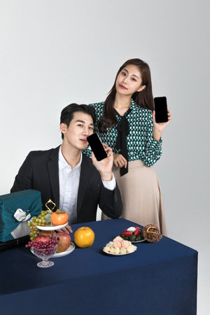 Korean young couple, man and woman wearing modern Hanbok_holding smartphone