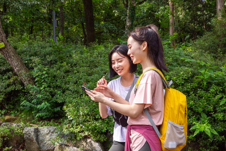 two Korean Asian female friends in 20s hiking and plogging in mountain__path finding using smartphoneの写真素材