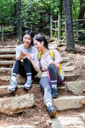 korean young women hiking and plogging_sitting down watching smartphoneの写真素材