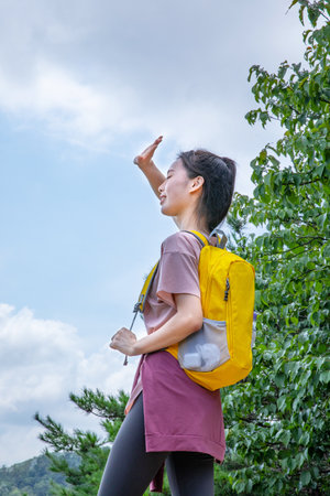 korean young women hiking and plogging-pointing sunの写真素材