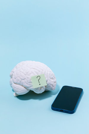 brain health and dementia series, a brain model with a question mark and a cell phoneの写真素材