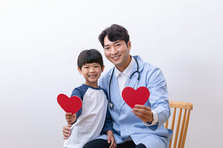 Asian Korean child and doctor holding a heart shape panelの写真素材