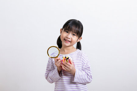 Asian Korean child with a magnifying glass and a tooth miniatureの写真素材