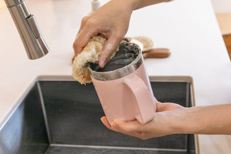 eco friendly habits hand gesture_wash the tumbler with an eco friendly sponge
