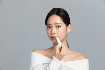 beautiful young Korean Asian woman portrait studio photo in winter skin beauty and cosmetics concept__put on lip balmの写真素材