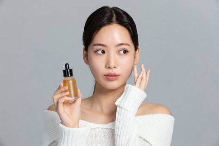 beautiful young Korean Asian woman portrait studio photo in winter skin beauty and cosmetics concept__holding an ampleの写真素材