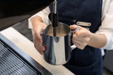 barista steaming milk for cafe latte in cafeの写真素材