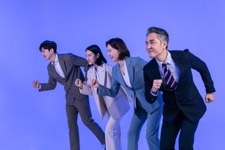 Asian Korean senior, middle aged and young male and female colleagues models in business attire, neon purple studio background, running motionの写真素材