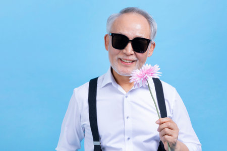 active young senior Korean Asian male holding flowersの写真素材