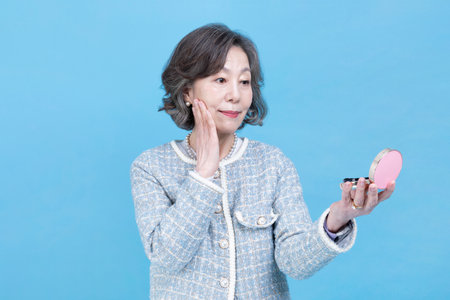 active young senior Korean Asian woman holding beauty cosmetic productsの写真素材