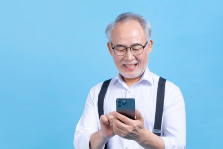 active young senior Korean Asian male looking at smartphoneの写真素材