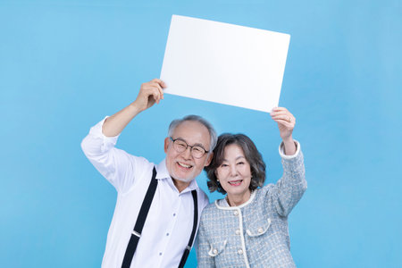 active young senior Korean Asian couple with copyspace boardの写真素材