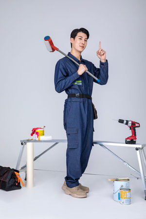 millennials and gen z, korean asian young man, site staff sitting holding a paint rollerの写真素材