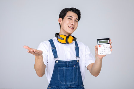 millennials and gen z, korean asian young man carpenter holding a calculatorの写真素材