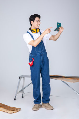 millennials and gen z, korean asian young man carpenter holding a bankbookの写真素材