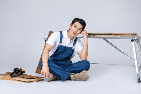 millennials and gen z, korean asian young man carpenter sittingの写真素材