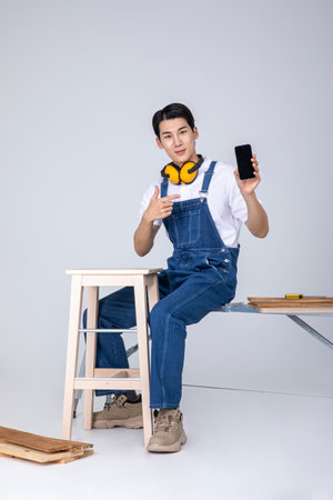 millennials and gen z, korean asian young man carpenter with a smartphoneの写真素材