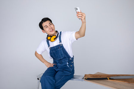 millennials and gen z, korean asian young man carpenter taking selfieの写真素材