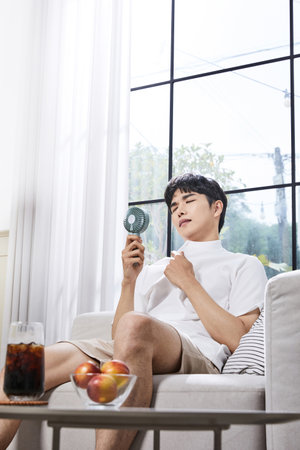 summer lifestyle, korean asian young man with handheld fanの写真素材