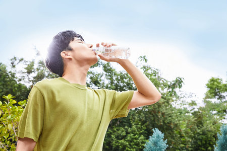 summer lifestyle, korean asian young man drinking water outdoorの写真素材