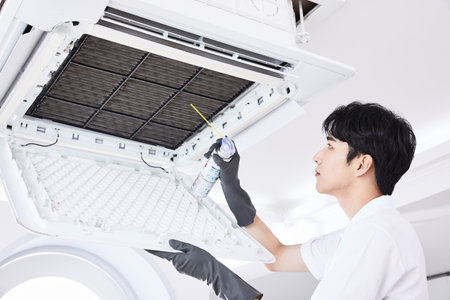 summer lifestyle, korean asian young man cleaning the air conditionerの写真素材