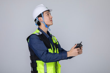 millennials and gen z, korean asian young man, site staff controlling a droneの写真素材