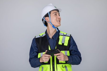 millennials and gen z, korean asian young man, site staff controlling a drone