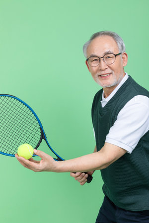 A senior male holding a tennis racket and a tennis ballの写真素材