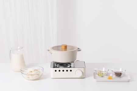 On a white table, there are ingredients and pots for rice cake soup