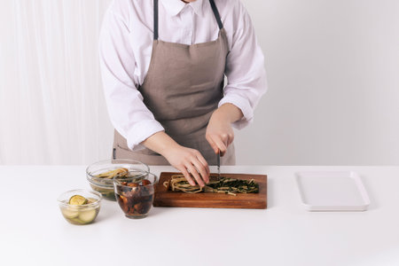 A woman is cutting a dried radish greens soaked in water with a knife