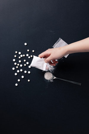a hand holding a plastic bag containing drugs