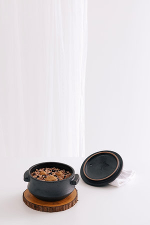 There is rice in an earthen pot and a lid is placed next to it