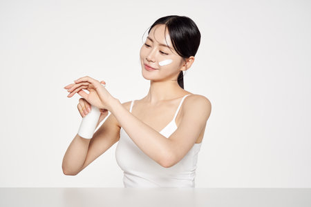 Asian Woman Poses to Apply Cosmetics on the Back of Her Handの写真素材