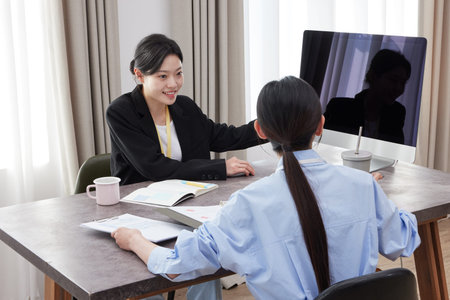 2 Asian Women Watching the Monitor and Meeting