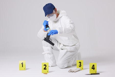 Evidence Marker A male researcher who checks evidence with a magnifying glass at the crime scene and at the incident siteの写真素材
