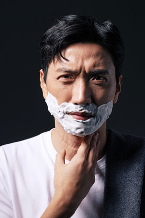 Middleaged man applying shaving cream to his face with one handの写真素材