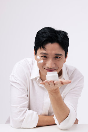 A middleaged man staring at the cream container in his palm with a smiling expressionの写真素材