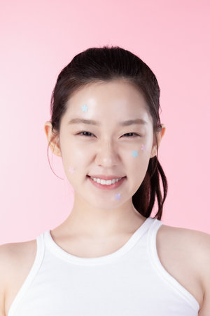 A teenage woman with a sticker on her face and a cute expression on her faceの写真素材