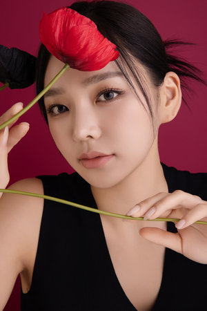 A woman in her 20s showing an elegant pose using poppy flowersの写真素材