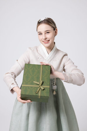 A foreign woman wearing traditional Korean hanbok holding a holiday giftの写真素材