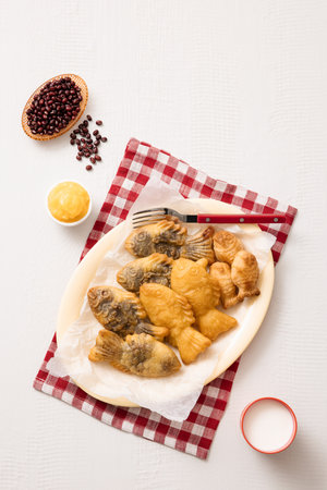 Red bean bungeoppang puff pastry and cream bungeoppang beautifully plated on a red checkered tableclothの写真素材