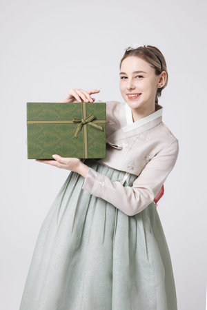 A foreign woman wearing traditional Korean hanbok holding a holiday giftの写真素材