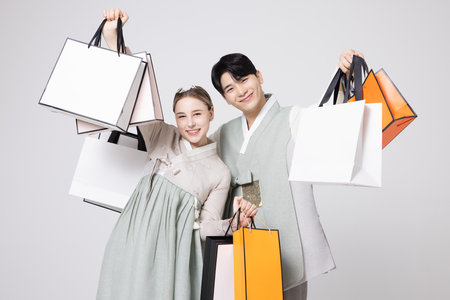 A foreign woman and a young Korean man wearing hanbok and holding shopping bags in both hands.の写真素材