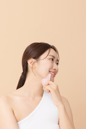 Portrait of a young woman massaging her skin using gua shaの写真素材