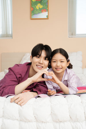 Dad and daughter posing on the bedの写真素材