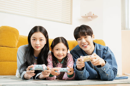 A young family lying down on the floor and playing a game together