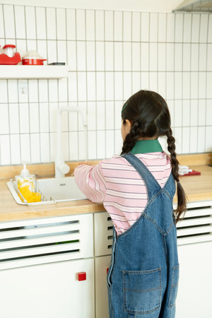 Back view of a child washing his hands in the kitchenの写真素材