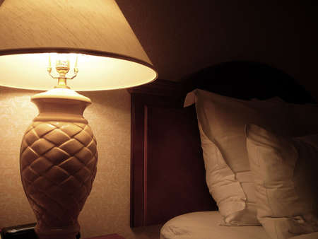 Cozy bedroom scene with bed, pillows and lampの写真素材
